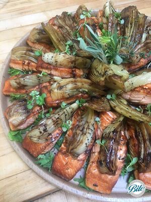 Overhead shot of pan-seared salmon with braised fennel & balsamic reduction in eco-friendly delivery tray